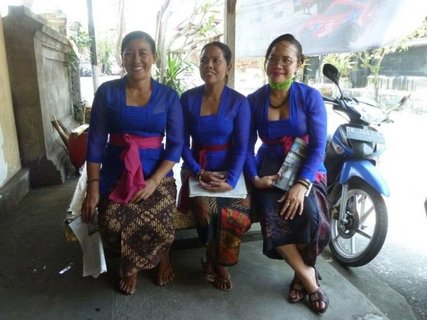 3 einheimische Frauen in ähnlicher Kleidung sitzen auf einer Bank