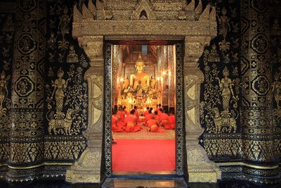 Mönche beten in einem buddhistischen Tempel vor einer großen goldenen Buddha-Statue