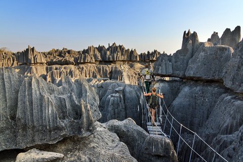 Zwei Wanderer überqueren eine Brücke im Kalksteinfelsengebirge auf Madagaskar