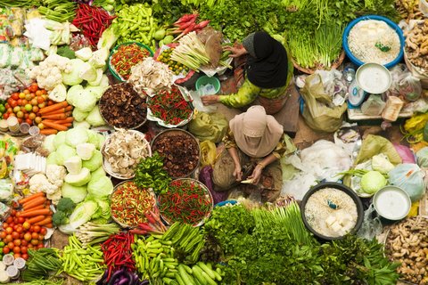 Händlerinnen auf einem Wochenmarkt in Kota Bharu, umringt von frischem Obst und Gemüse.