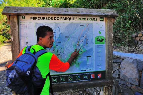 Ein Kapverdianer im neonfarbenen T-Shirt zeigt auf einer Karte einen Wanderweg im Nationalpark Serra Malagueta.