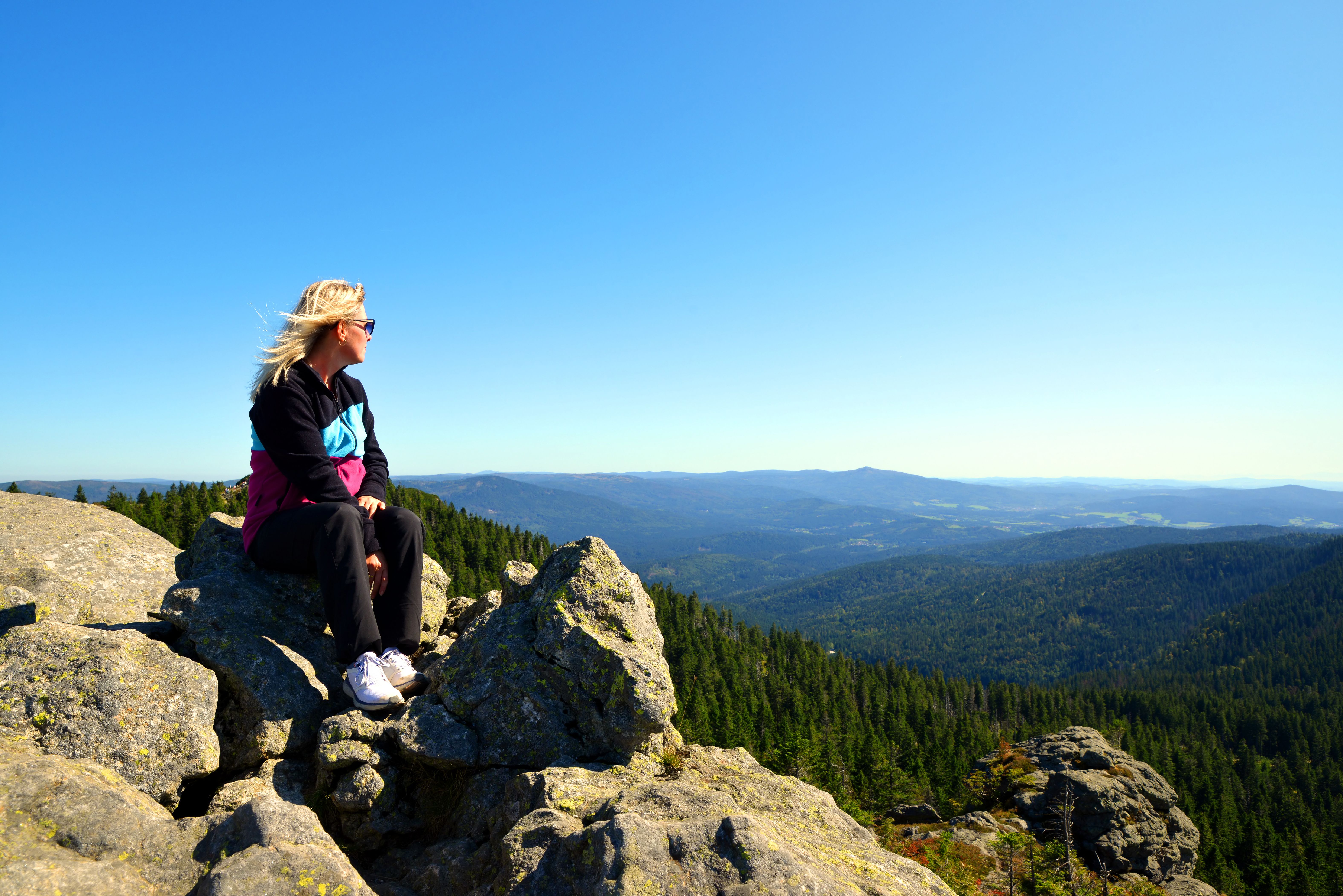 Auf dem Gipfel des Großen Arber im Bayerischer Wald Frau sitzt auf dem Gipfel des Großen Arber im Bayerischer Wald und genießt den Blick in die Ferne