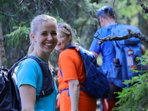 Drei Wanderer im Wald, eine blickt lächelnd in die Kamera