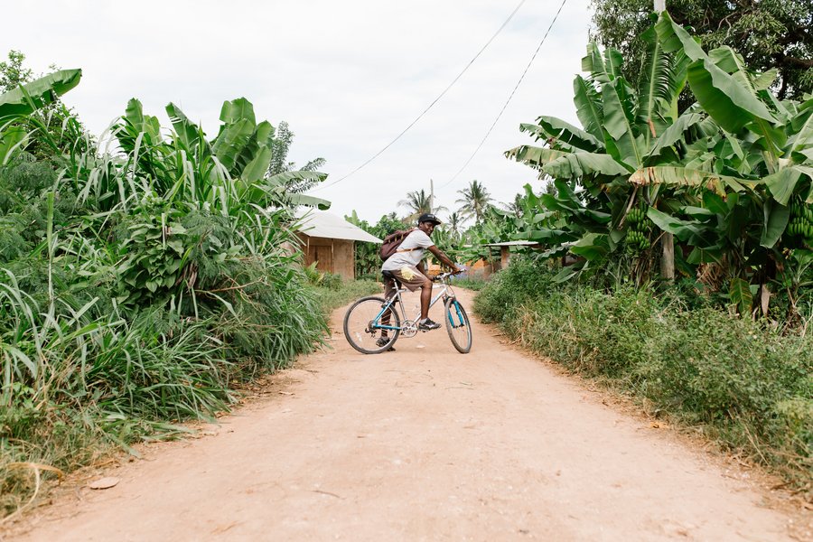 Fahrradfahrer auf einer kleinen Straße in dem Dorf Nungwi auf Sansibar.