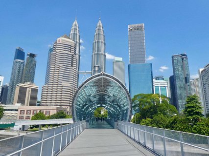 Von einem Ende einer Fußgängerbrücke schaut man auf die Skyline auf der anderen Seite, die vor allem aus futuristisch anmutenden Hochhäusern besteht.