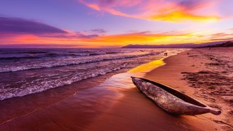Abendstimmung am Malawisee Ein traditionelles Holzboot ruht auf der glatten Oberfläche des Malawisees, während der Sonnenuntergang den Himmel in warmen Orange- und Goldtönen färbt. Die sanften Wellen und die friedliche Stille der Umgebung schaffen eine malerische und besinnliche Atmosphäre.