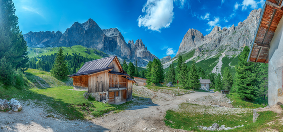 Auf eindrucksvollen, doch nicht zu schweren Wegen durch den Rosengarten Von links vorne führt ein Wanderweg in den Bildmittelgrund. Links des Wegs steht eine Berghütte, im Hintergrund erhebt sich der Rosengarten.