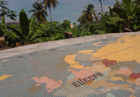 Eine mit bunten Plättchen dargestellte Karte auf dem Boden. Von dieser Plattform ist ein Ausblick auf sattgrüne Palmen und das blaue Meer.