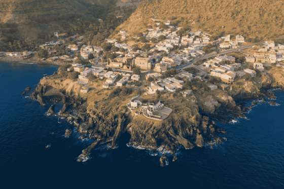 Man sieht die Luftaufnahme einer Ortschaft an einer Küste, die sich teilweise auf einer Halbinsel ins Meer erstreckt.