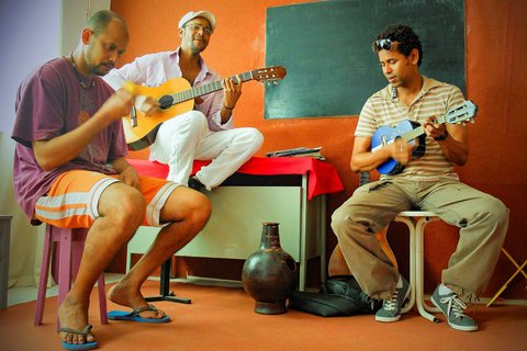 Drei Musiker musizieren gemeinsam, zwei spielen Gitarre, einer Rassel.