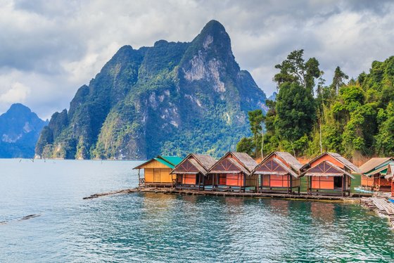 See mit aneinandergereihten roten Bungalows und grünem Berg im Hintergrund