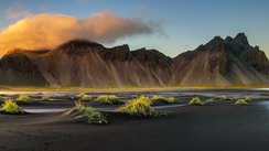 Eine Landschaft mit einem Gebirge und einem Gewässer im Vordergrund