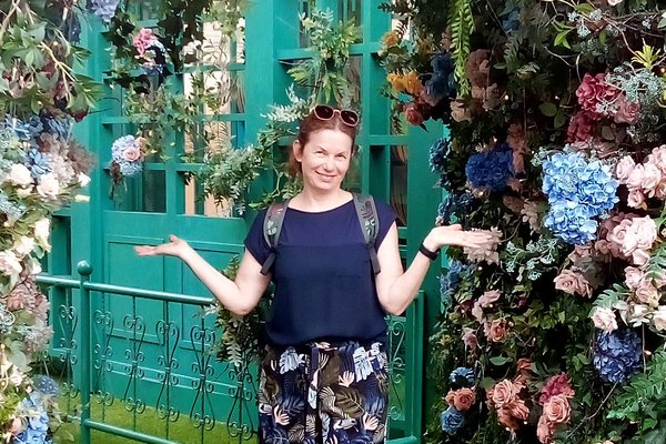Reiseberaterin Sabine Kersken lächelnd vor einer Blumenranke