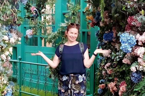 Reiseberaterin Sabine Kersken lächelnd vor einer Blumenranke