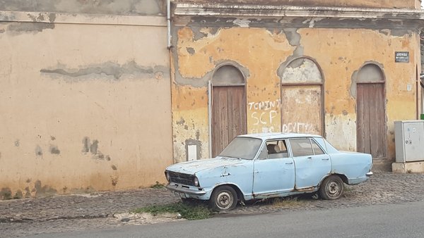 Ein altes Auto steht auf einer Straße in einer kapverdischen Stadt.