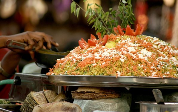Kulinarisch vegan: Streetfood in Indien Person bedient sich an einem hübsch angerichteten veganen Reisteller.