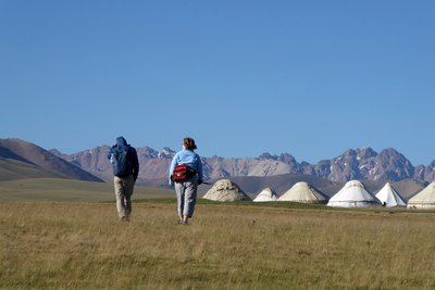 Zwei Touristen laufen über eine Wiese zum Jurtencamp