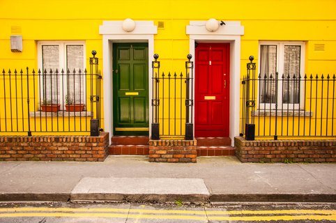 gelbe Hausfassade mit roter und grüner Holztür