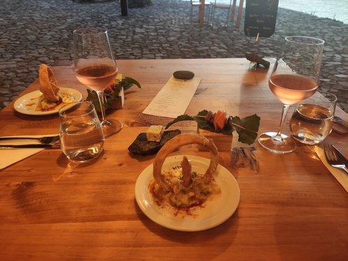 Auf einem Holztisch stehen schön angerichtet zwei Teller mit vegetarischem Essen flankiert von Wein- und Wassergläsern.