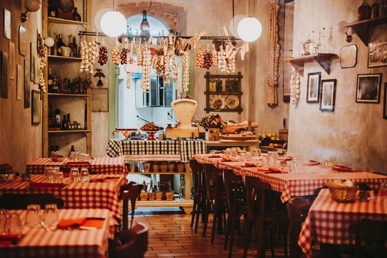 Eine gemütliche, inhabergeführte Trattoria in Italien Mehrere Tische mit karierten Tischdecken stehen in einem kleinen Restaurant.