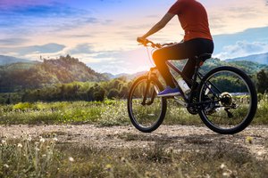 Radfahrer fährt auf einem Feldweg in der Natur.