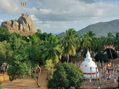 Die Klosteranlage Mihintale Eingestreut zwischen Palmen und Bäumen liegen Gebäude einer buddhistischen Klosteranlage, im Vordergrund rechts ein weißer Stupa.