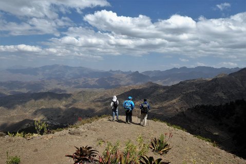 Drei Wanderer stehen an einer Klippe und haben einen Panoramerausblick über die Lasta Berge in Äthiopien.