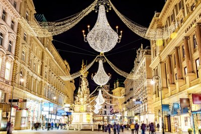 Eine Einkaufsstraße flankiert von prächtiger historischer Architektur, die mit Kristalllüstern beleuchtet wird.