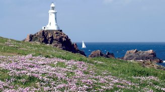 Weißer Leuchtturm auf einem Felsen am Meer