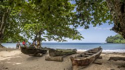 Holzboote am Strand Praia da Colónia Açoriana von São Tomé und Príncipe Holzboote unter Bäumen am Strand