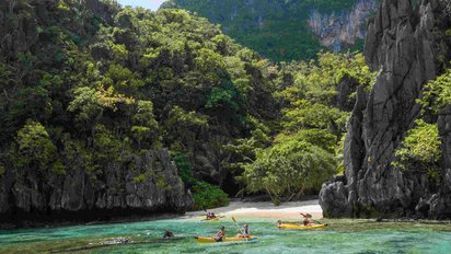 Menschen in Kajaks vor einem Bergpanorama