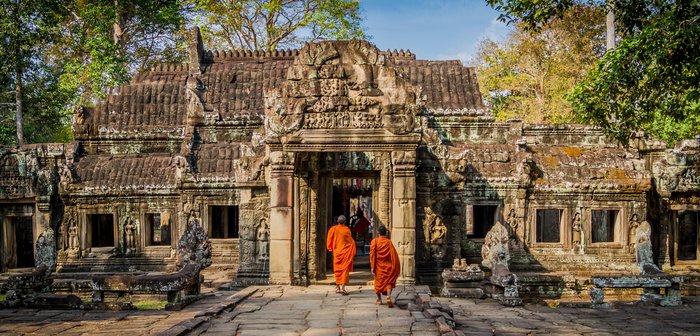 Zwei Mönche laufen auf einem Weg auf einen alten Tempel zu