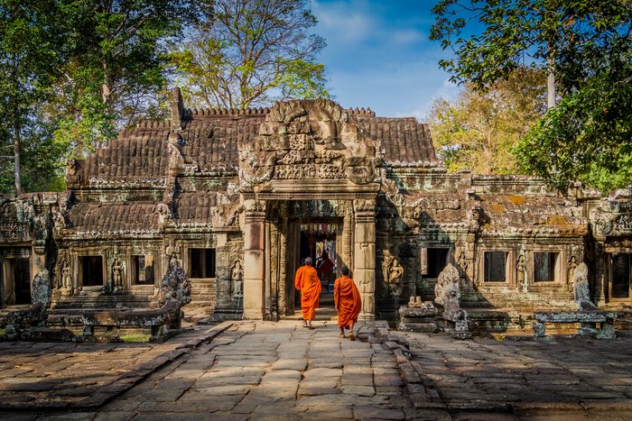 Zwei Mönche laufen auf einem Weg auf einen alten Tempel zu