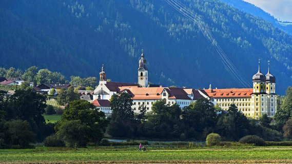 Stift Stams Kloster in den Tiroler Alpen Das barocke Kloster Stift Stams in Tirol, Österreich, mit seinen markanten Zwiebeltürmen, umgeben von grünen Wiesen und Bergen.