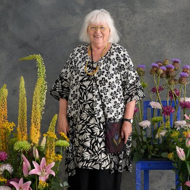 Eine Frau steht neben Blumen und lächelt in die Kamera