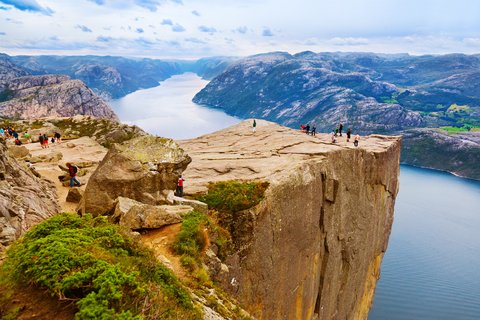 auf einer sehr hohen und spitzen Klippe am Fjord stehen Wandergruppen