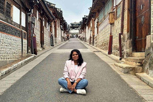 Unsere Reiseberaterin Assvini sitzt im Schneidersitz auf einem Weg in Asien.