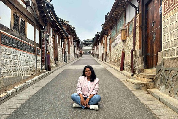 Unsere Reiseberaterin Assvini sitzt im Schneidersitz auf einem Weg in Asien.