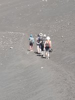 Wanderung auf den Pico do Fogo Inmitten grauen Lavagerölls bewegt sich eine kleine Gruppe vom Betrachter weg.