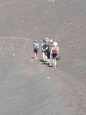 Inmitten grauen Lavagerölls bewegt sich eine kleine Gruppe vom Betrachter weg.