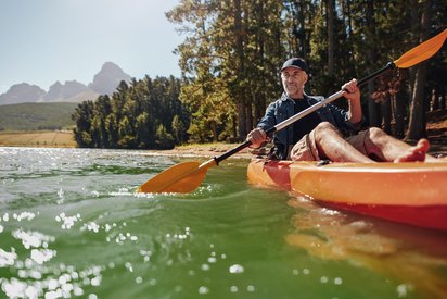 Aktiv in der Natur mit dem Kayak Ein Mann fährt Kayak auf einem See im Sommer.