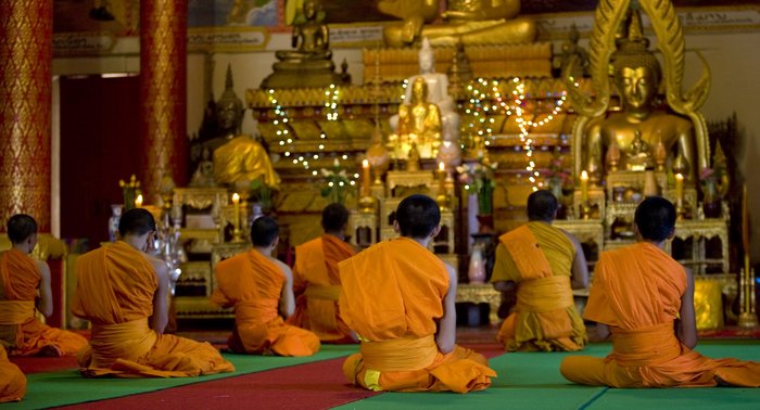 Mönche beten vor Buddha Statuen in einem Tempel
