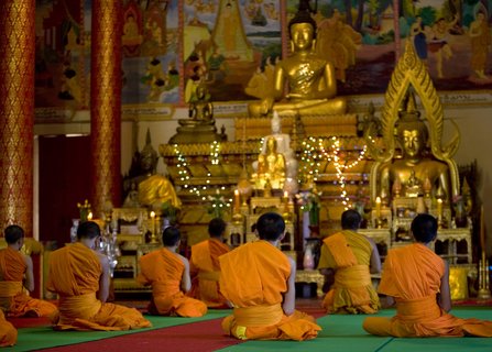 Mönche beten vor Buddha Statuen in einem Tempel