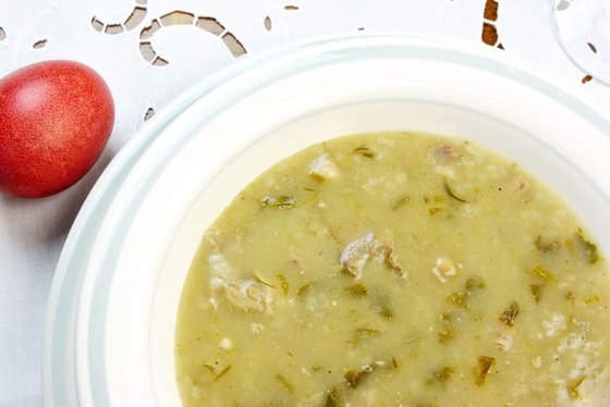 Ein Teller voll Suppe neben einem rot angemalten Ei