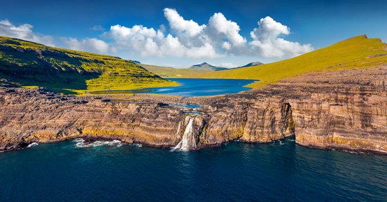 Der Wasserfall Bøsdalafossur auf den Färöer-Inseln Ein 30 Meter hoher Wasserfall stürzt von einer Insel in den Atlantik
