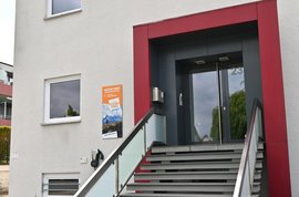 Foto des Hauseingangs vom neuen Büro in Dortmund. Eine Treppe führt zur Haustür und neben der Treppe befindet sich eine angebrachte Wallbox.
