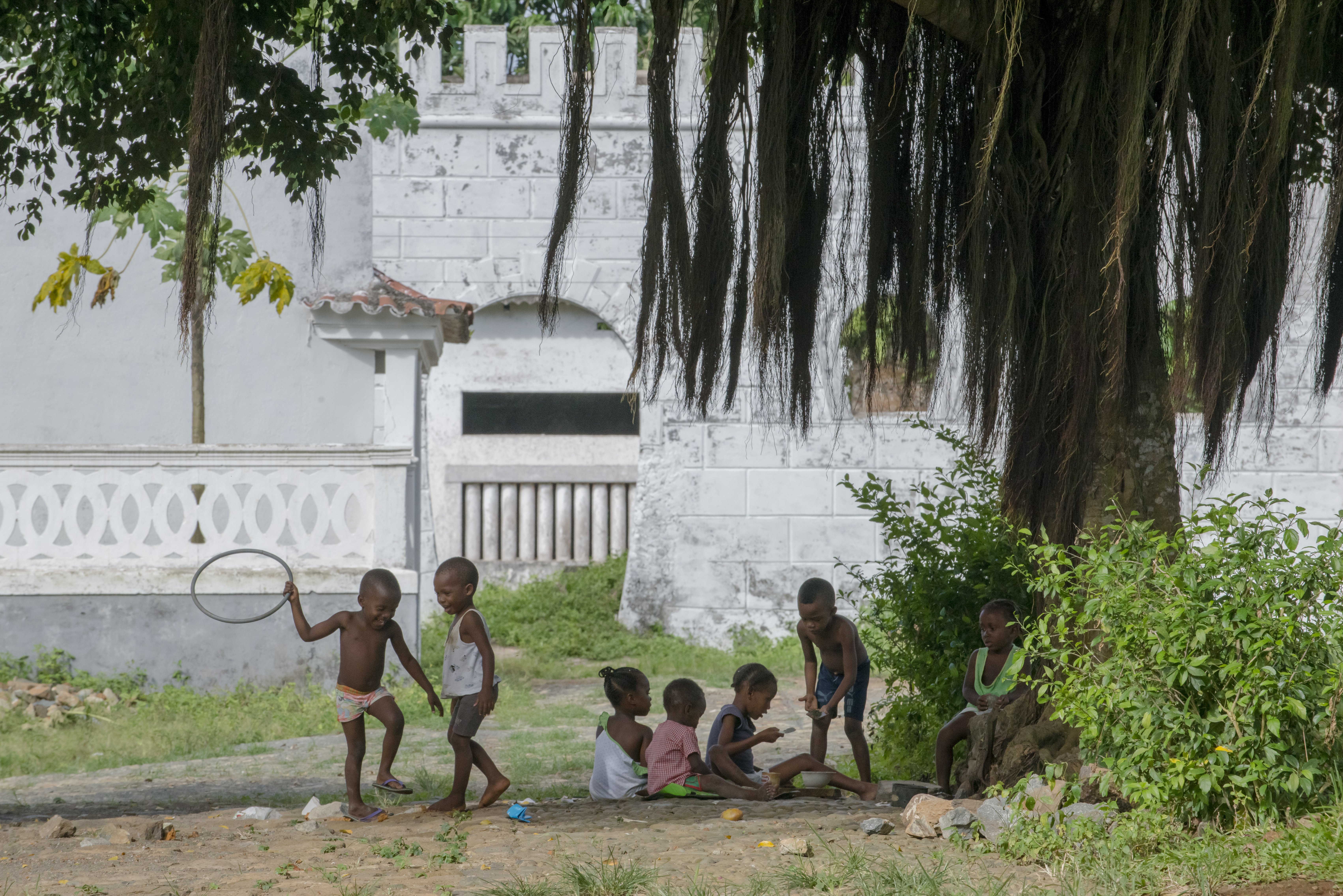 Spielende Kinder unter einem Baum auf dem Gelände einer Roça