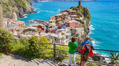 Eine Frau und ein Mann genießen den Blick auf das Meer und bunte Häuser in Cinque Terre