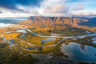 Aus der Vogelperspektive blickt man auf eine weit ausgedehnte Fluss- und Berglandschaft.