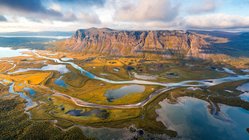 Aus der Vogelperspektive blickt man auf eine weit ausgedehnte Fluss- und Berglandschaft.